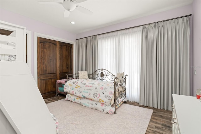 bedroom with dark hardwood / wood-style floors, a closet, and ceiling fan