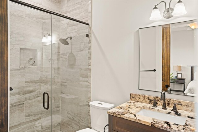 bathroom with vanity, a shower with door, and toilet