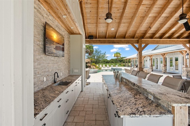 view of patio / terrace with a pool, ceiling fan, french doors, and sink