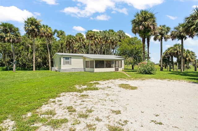 rear view of house featuring a yard and a sunroom