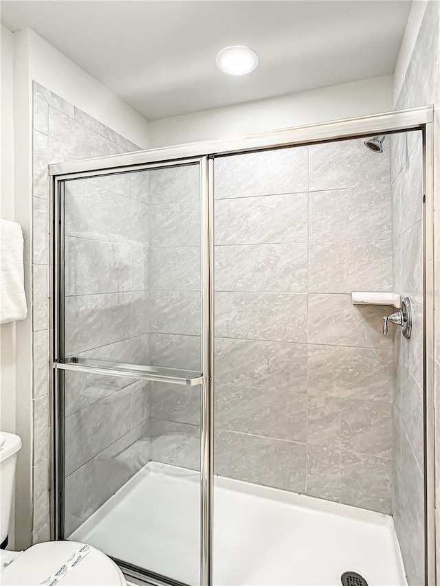 bathroom featuring an enclosed shower and toilet