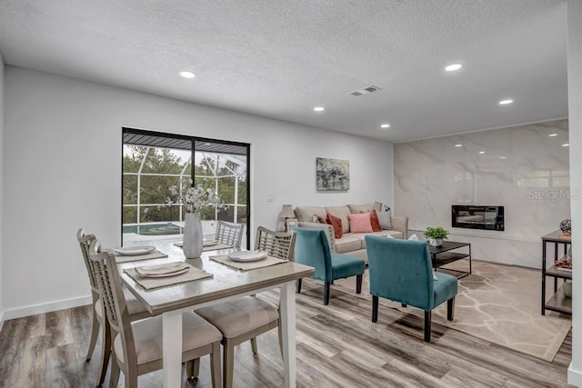 dining space featuring light hardwood / wood-style floors and a textured ceiling