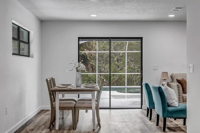 dining room with light hardwood / wood-style flooring and a textured ceiling