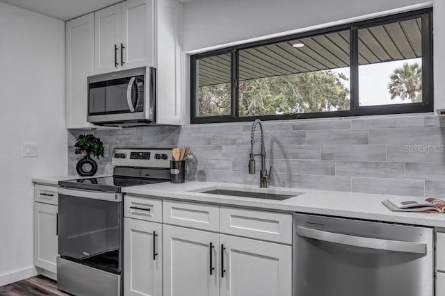 kitchen with stainless steel appliances, white cabinetry, dark hardwood / wood-style flooring, backsplash, and sink