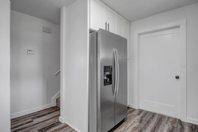 kitchen featuring stainless steel fridge, dark wood-type flooring, and white cabinetry