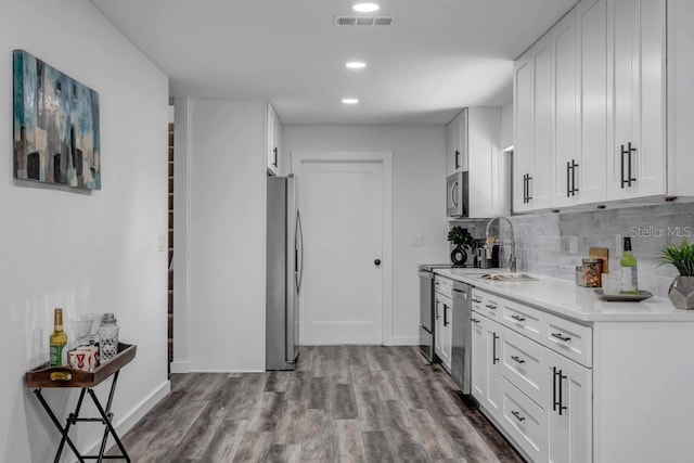 kitchen with hardwood / wood-style flooring, tasteful backsplash, appliances with stainless steel finishes, white cabinetry, and sink