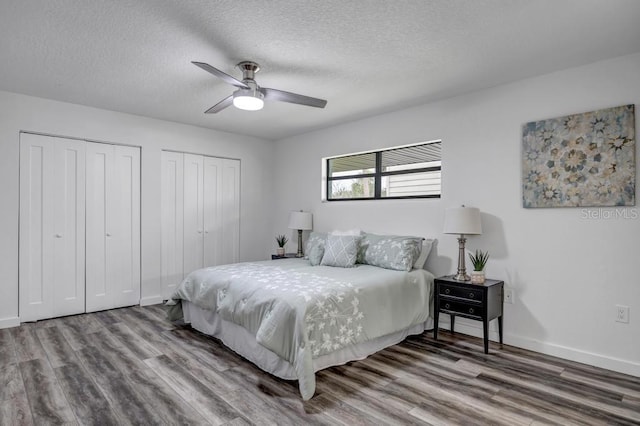 bedroom featuring multiple closets, a textured ceiling, wood-type flooring, and ceiling fan