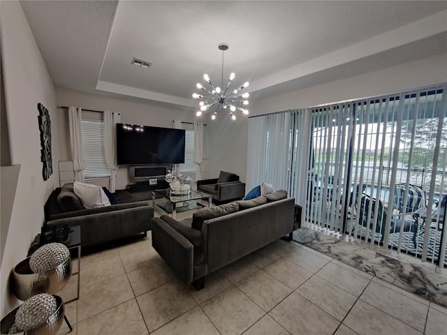 living room with a chandelier, a raised ceiling, and light tile floors