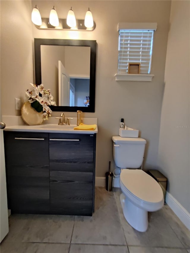 bathroom with toilet, vanity, and tile flooring