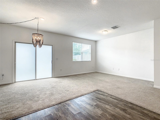 empty room featuring an inviting chandelier, carpet flooring, and a textured ceiling