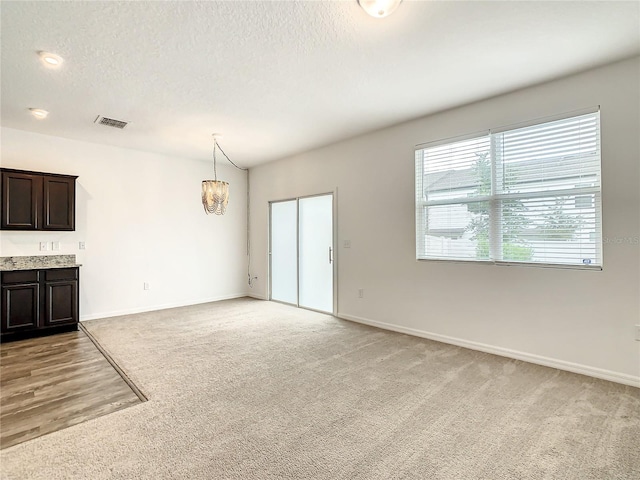 unfurnished living room with light carpet and a textured ceiling