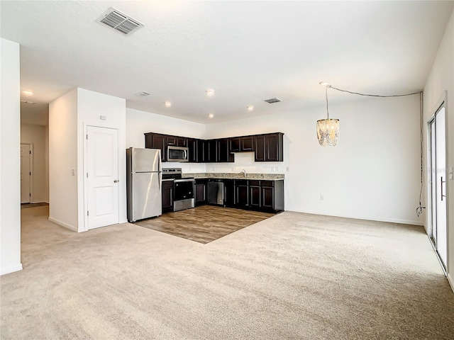 kitchen featuring hanging light fixtures, sink, stainless steel appliances, dark brown cabinets, and light colored carpet