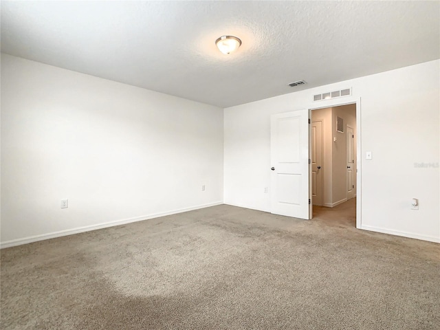 empty room with carpet floors and a textured ceiling