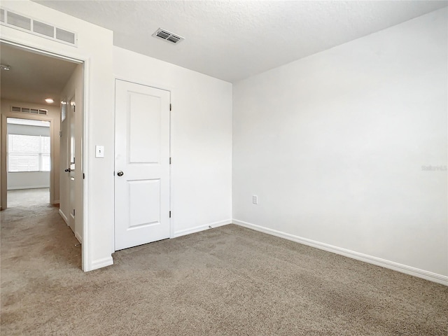 carpeted empty room with a textured ceiling