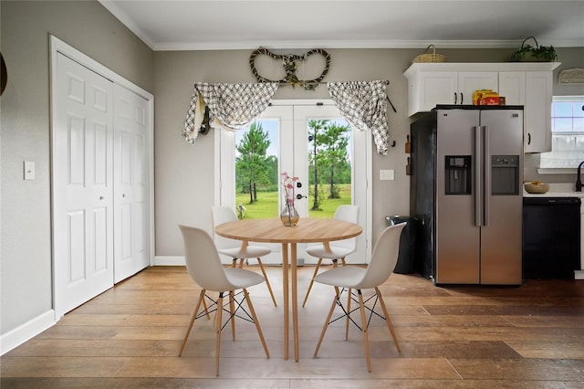 dining space featuring crown molding and light hardwood / wood-style floors