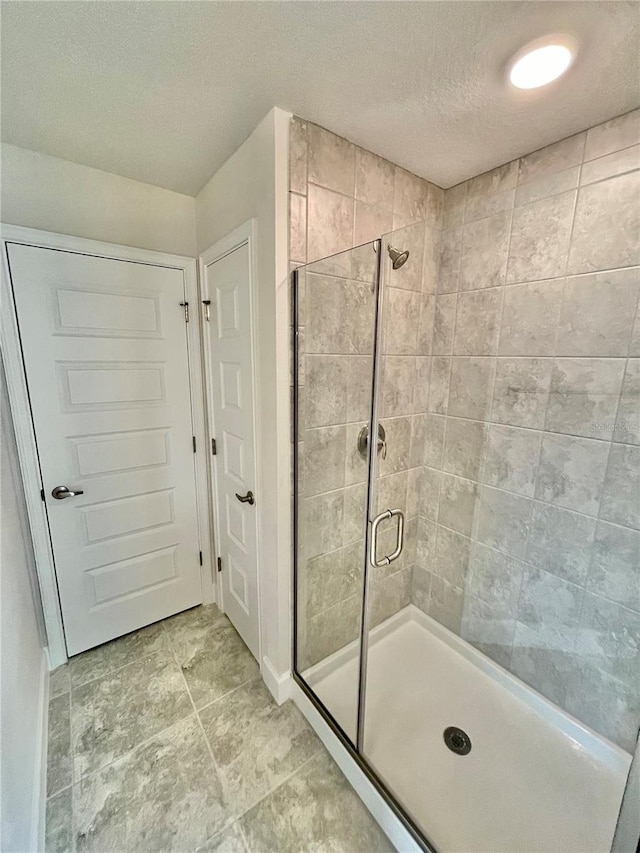 bathroom with tile floors, a shower with shower door, and a textured ceiling