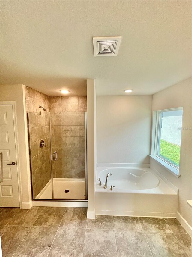 bathroom featuring a textured ceiling, tile floors, and plus walk in shower