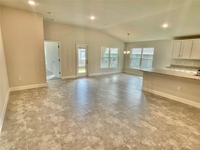 tiled empty room with an inviting chandelier and lofted ceiling