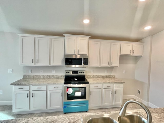 kitchen with stainless steel appliances, white cabinets, and light tile floors