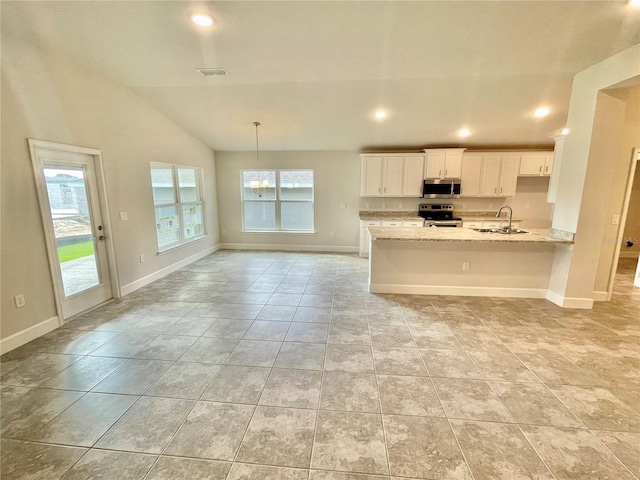 kitchen featuring lofted ceiling, light tile floors, appliances with stainless steel finishes, white cabinets, and sink