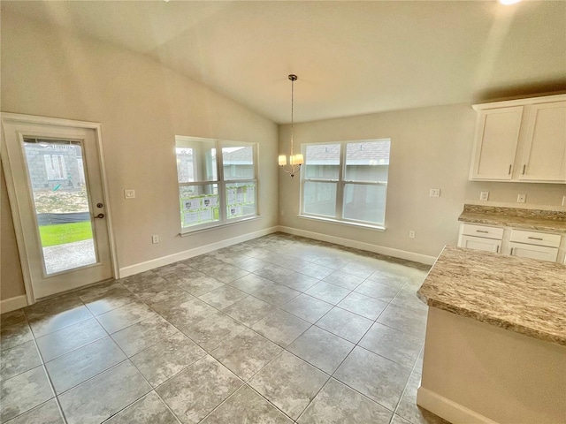 kitchen featuring light stone countertops, light tile flooring, white cabinets, vaulted ceiling, and pendant lighting