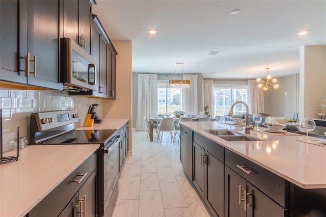 kitchen with a chandelier, pendant lighting, light tile flooring, appliances with stainless steel finishes, and sink