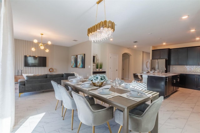 dining area featuring sink, a notable chandelier, and light tile flooring