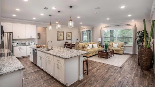 kitchen featuring hanging light fixtures, a center island with sink, ornamental molding, appliances with stainless steel finishes, and white cabinets