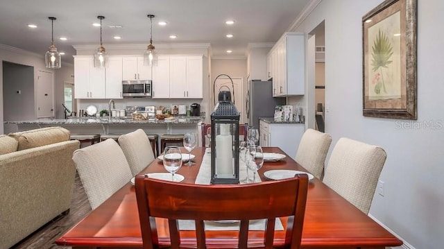 dining room featuring hardwood / wood-style flooring, ornamental molding, and sink