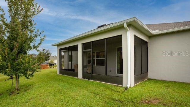 back of house with a sunroom and a lawn