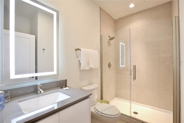 bathroom featuring vanity, a shower with shower door, and toilet