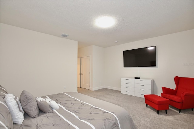 bedroom featuring a textured ceiling and light colored carpet