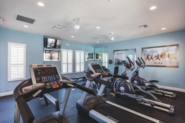 workout area featuring dark carpet, ceiling fan, and a wealth of natural light