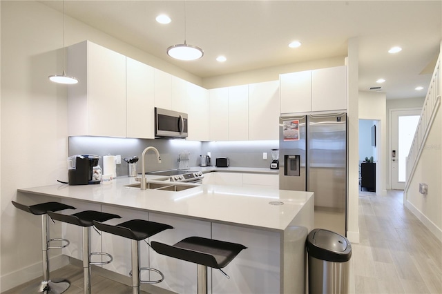 kitchen featuring appliances with stainless steel finishes, decorative light fixtures, and white cabinetry