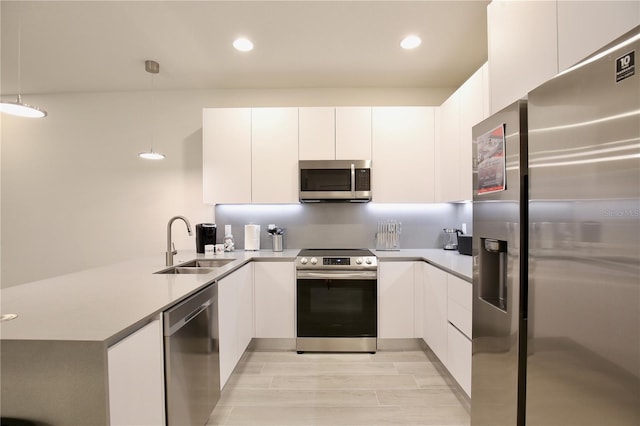 kitchen featuring white cabinetry, hanging light fixtures, sink, and stainless steel appliances