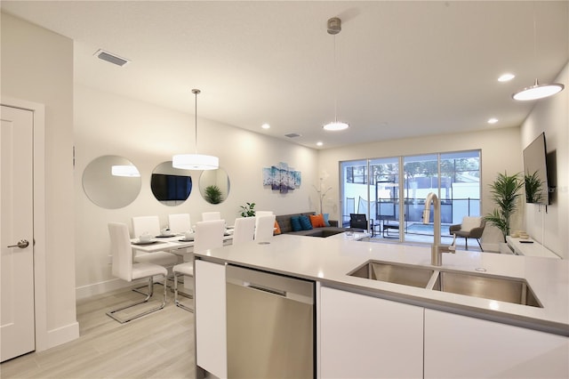 kitchen featuring stainless steel dishwasher, light hardwood / wood-style flooring, white cabinetry, hanging light fixtures, and sink