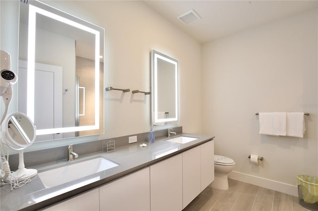 bathroom featuring double sink vanity, wood-type flooring, and toilet