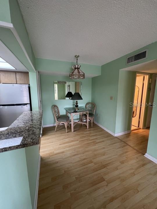 dining space with light hardwood / wood-style floors, a textured ceiling, and a skylight