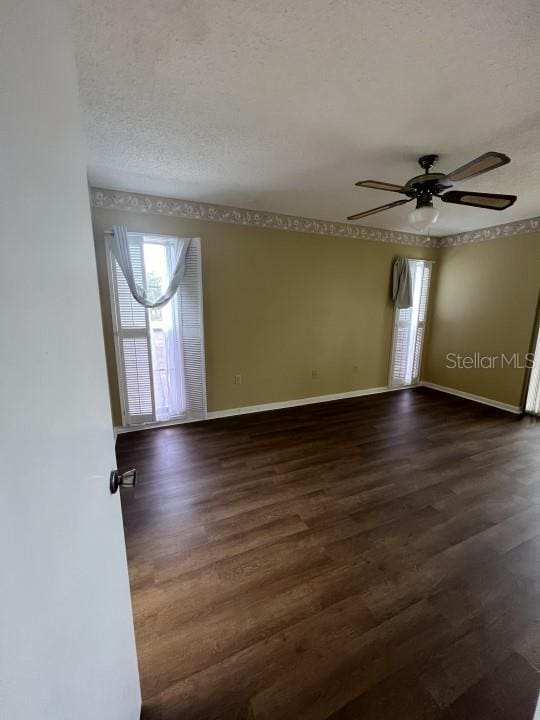 unfurnished room with a textured ceiling, dark hardwood / wood-style floors, and ceiling fan