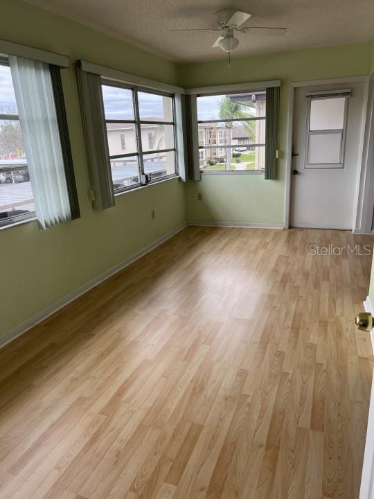 unfurnished room featuring a wealth of natural light, a textured ceiling, light hardwood / wood-style floors, and ceiling fan