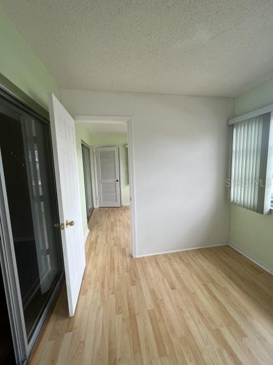 spare room with a textured ceiling and light wood-type flooring