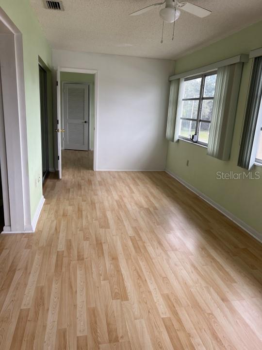 spare room featuring a textured ceiling, light wood-type flooring, and ceiling fan