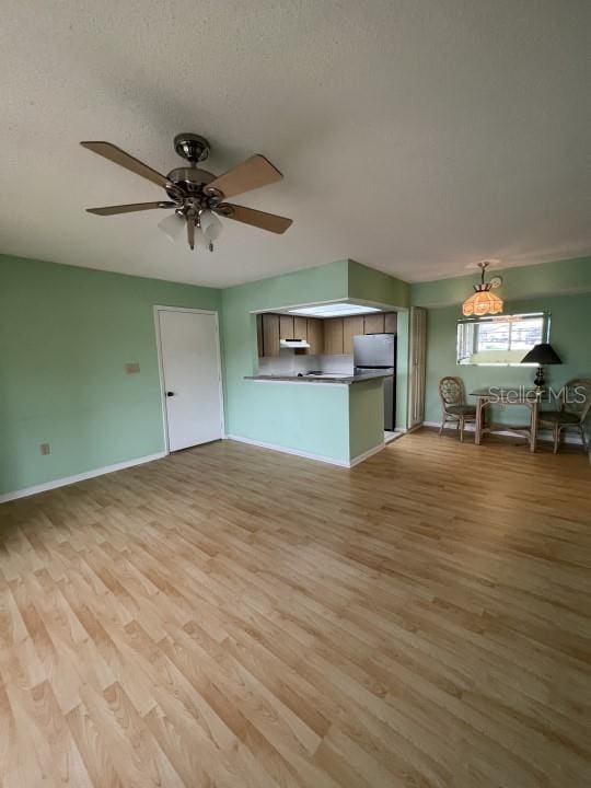 unfurnished living room featuring light hardwood / wood-style flooring, a textured ceiling, and ceiling fan