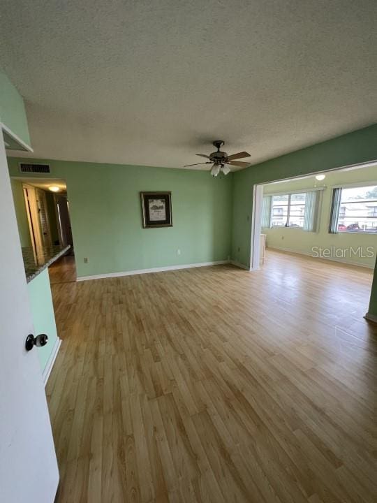 unfurnished living room with a textured ceiling, light hardwood / wood-style floors, and ceiling fan