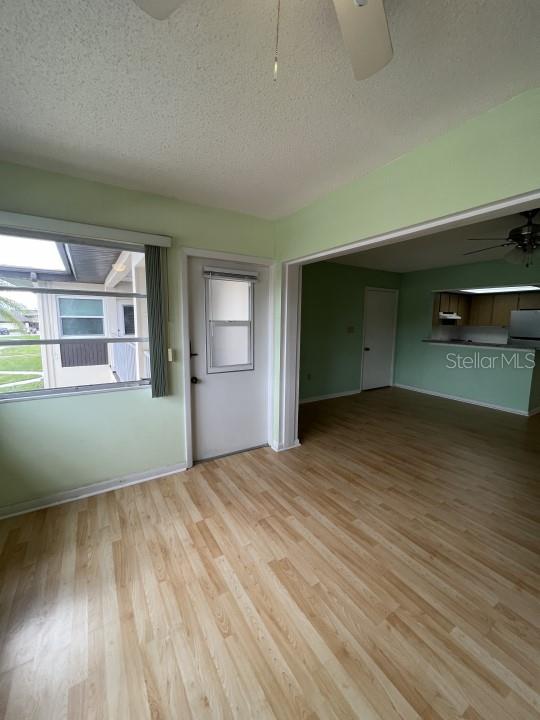 unfurnished living room featuring light hardwood / wood-style floors, a textured ceiling, and ceiling fan