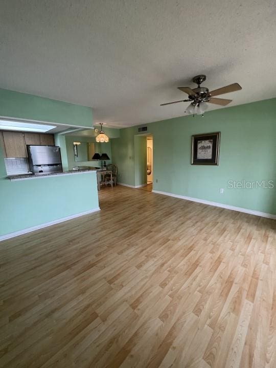 unfurnished living room with light hardwood / wood-style flooring, a textured ceiling, and ceiling fan