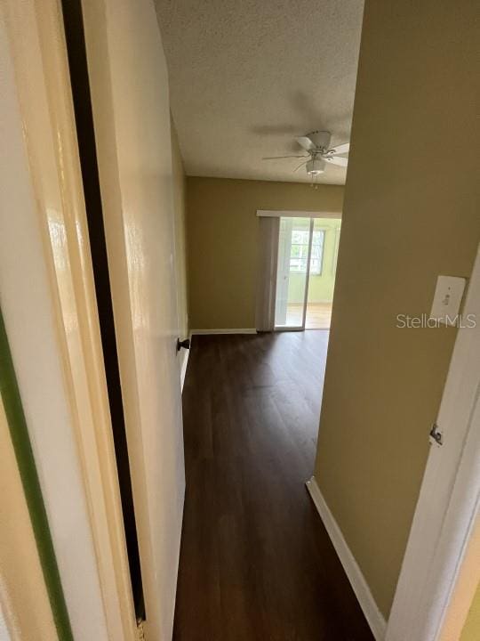 hallway with a textured ceiling and dark hardwood / wood-style flooring