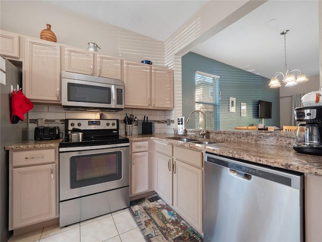 kitchen featuring sink, vaulted ceiling, hanging light fixtures, light tile patterned floors, and stainless steel appliances