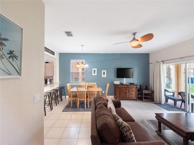 tiled living room with ceiling fan with notable chandelier