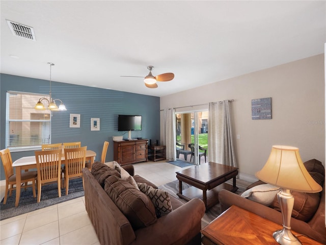 tiled living room with ceiling fan with notable chandelier